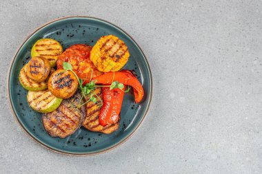 Arka planda hafif bir tabakta çeşitli ızgara sebzeler, üst manzara. Boşluğu kopyala.