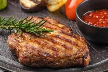 Izgara domuz bifteği, otlar ve domates sosu. Kapatın. en üstteki görünüm.