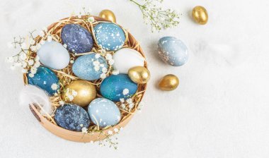 Karton bir paketin içine boyanmış Paskalya yumurtaları ve açık arkaplanda çiçekler. Mutlu Paskalyalar. Boşluğu kopyala.