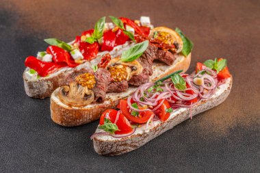 Çeşitli malzemelerle çeşitli bruschetta. Koyu arkaplanda İtalyan antipasti atıştırmalıkları olan aperatifler. Üst Manzara. metin için boşluk kopyala.