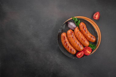 Koyu arkaplanda domatesli ızgara sosisler, üst görünüm, kopyalama alanı,