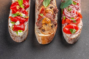 Çeşitli malzemelerle çeşitli bruschetta. Koyu arkaplanda İtalyan antipasti atıştırmalıkları olan aperatifler. Üst Manzara. metin için boşluk kopyala.