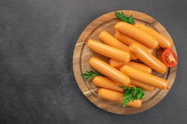 Ahşap bir tahtada kaynamış lezzetli sosis, karanlık bir arka planda. Üst Manzara. Boşluğu kopyala,