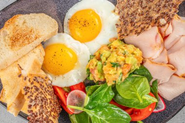 Yağda yumurta, jambon, avokado ve taze salata. Lezzetli dengeli kahvaltı. en üstteki görünüm.