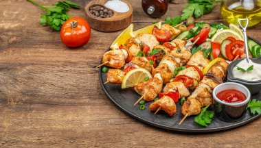 Ahşap bir arka planda ızgara tavuk ya da hindi şiş salatası, sos, otlar ve baharatlar. Boşluğu kopyala.