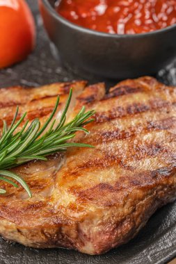 Biberiyeli domuz pirzolası ve siyah tahtada domates sosu..