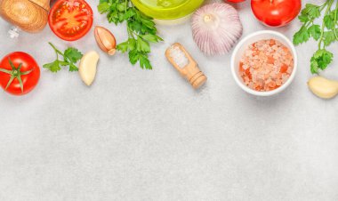 Mutfak tezgahında domates, sarımsak, maydanoz, tuz, soğan, biber ve zeytinyağı pişirmek için taze malzemeler hazır. Üst Manzara. Boşluğu kopyala.