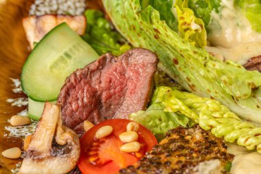 Taze sebzeli, mantarlı ve çam fıstıklı orta pişmiş biftek salatası..