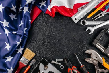 Amerika Birleşik Devletleri 'nde işçiliği, zanaatkarlığı ve vatanseverliği simgeleyen, karanlık bir arkaplanda ulusal bayrak etrafında düzenlenmiş Amerikan araçları,.