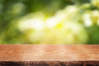 Pürüzsüz ahşap bir masa seti, parlak, güneş lekeli yeşil bir zemin, doğal ürünleri sergilemek için mükemmel, ya da yaz temalı içerik.