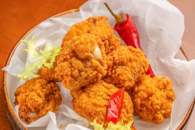 Kızarmış tavuk parçaları kırmızı biberle servis edilir ve ekstra lezzet ve doku için taze frizbi maruluyla süslenir.