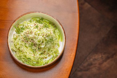 Taze öğütülmüş lahana salatası, ayçiçeği tohumları ve dereotuyla hafif ve besleyici bir yemek seçeneği için yeşil otla servis edilir..