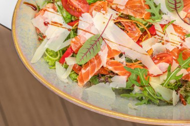 Somon, parmesan peyniri, roka, vişneli domates ve yeşillik dilimli canlı taze bir salata..