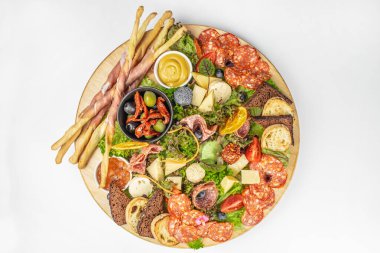 Renkli bir şarküteri tahtası güzel bir şekilde hazırlanmış et, peynir, ekmek, ekmek, ekmek, zeytin, güneşte kurutulmuş domates, taze yeşillikler ve çeşitli meyvelerle..