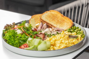 Yağda yumurta, biftek, peynir, taze salata, edamame, salatalık kurdelesi ve kızarmış ekmek ile doyurucu ve renkli bir kahvaltı tabağı..