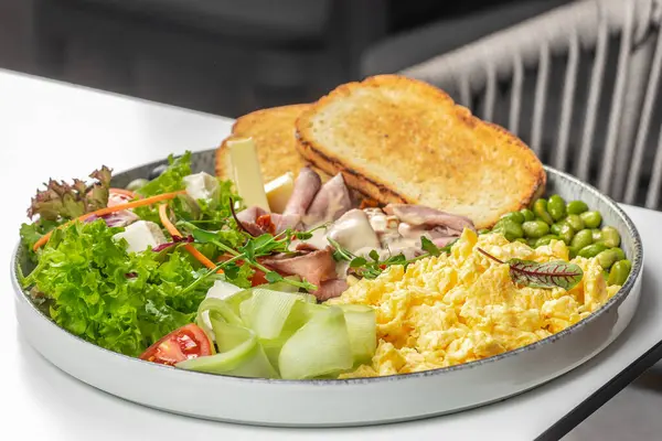 Yağda yumurta, biftek, peynir, taze salata, edamame, salatalık kurdelesi ve kızarmış ekmek ile doyurucu ve renkli bir kahvaltı tabağı..