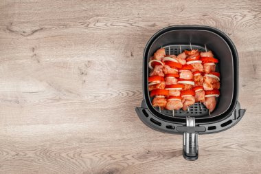 Çiğ tavuk ve sebze şişleri, ahşap mutfak tezgahında sağlıklı ve kullanışlı pişirmeye hazır bir tava sepeti içinde güzelce düzenlenir..