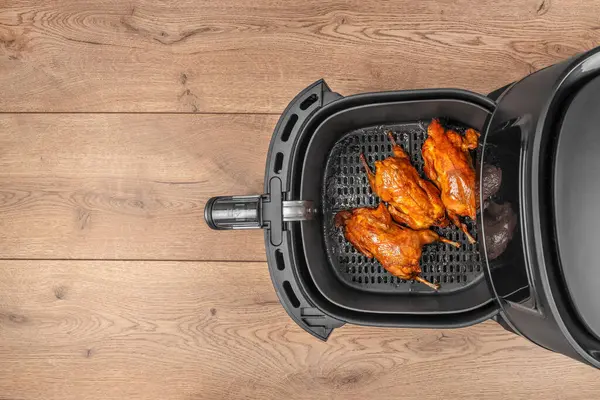 Üç mükemmel kavrulmuş bıldırcın, altın sarısı, çıtır çıtır derili, ahşap bir arka planda hizmet vermeye hazır bir tava sepetinin içinde..