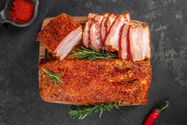 Köy sunumu için ahşap bir kesme tahtasının üzerinde taze biberiyeyle süslenmiş, kırmızı baharatlı kıtır kıtır domuz eti..