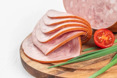 Yumuşak desenli ve portakal kabuklu ince dilimler taze yeşil soğanlar ve yarım kiraz domatesi eşliğinde ahşap bir kesme tahtasının üzerinde dinleniyor..