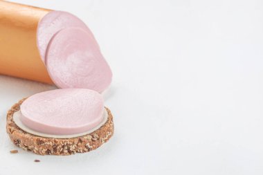 Susam tohumlu tam tahıllı ekmeğin üzerine bir dilim pembe sucuk yakın plan, temiz beyaz arka plan üzerine kurulmuş. Üst Manzara. Boşluğu kopyala.