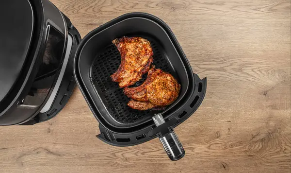 İki baharatlı domuz pirzolası, ahşap mutfak tezgahında, açık bir hava tavasında duruyor..