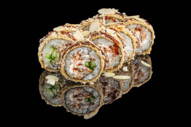 Krem peynirle, salatalıkla ve deniz ürünleriyle dolu çıtır suşi ruloları altın tempura ile kaplıdır, sosla ıslatılır ve parlak siyah bir yüzey üzerine badem dilimleri ile süslenir..