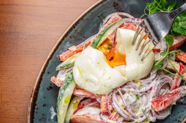 Yumuşak kaynamış yumurtayla kaplanmış taze sebzeli canlı bir salata. Zengin, cıvık bir sarıyı ortaya çıkarmak için delinmiş..