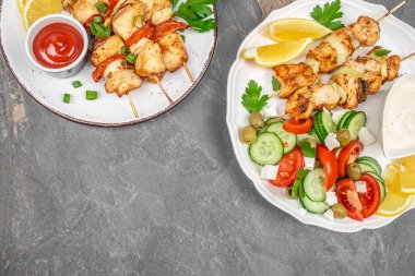 Taze salatayla servis edilen ızgara tavuk şişleri, limon dilimleri ve kırsal tabaklara batırılmış soslar. Boşluğu kopyala, üst görünüm.