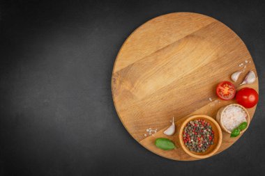 Siyah zemin üzerinde tuz, biber, domates, sarımsak ve fesleğen olan ahşap tahta manzarası. Metin için boşluk