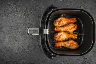 Koyu dokulu arka planda otlarla birlikte bir kızartma makinesinde pişirilmiş dört altın sarısı tavuk budu. Üst Manzara. Boşluğu kopyala.