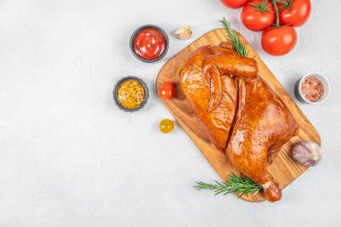 Ahşap bir tahtada tütsülenmiş tavuk taze biberiye, kiraz domatesleri, sarımsak, ketçap, hardal ve açık arkaplanda tuz. Boşluğu kopyala.