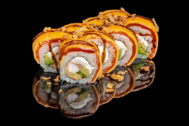 Renkli suşi ruloları üzerinde canlı portakal sosu, krem peynir, avokado ve parlak siyah bir yüzey üzerinde çıtır soğan..