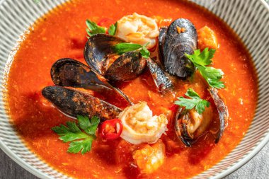 Karides, midye, kırmızı biber dilimleri ve domates suyunda maydanoz içeren zengin bir deniz ürünleri çorbası. en üstteki görünüm.