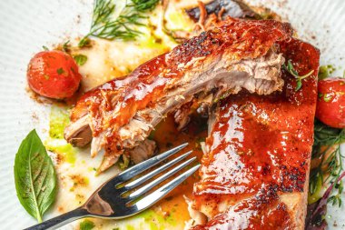 Dumanlı ızgara kabuklu yumuşak soslu domuz pirzolası, kiraz domatesleri, otlar ve beyaz tabakta canlı bir sos ile servis edilir. en üstteki görünüm.