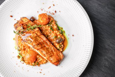 İnci kuskus yatağında servis edilen ızgara somon filetosu, kiraz domatesleri, otlar ve baharatlı sos. Üst Manzara. Boşluğu kopyala.