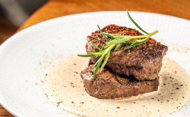 Izgara fileminyon biftek, kremalı biber sosu ve biberiye garnitürle servis edilir. Boşluğu kopyala