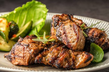 Taze yeşillik ve seramik tabakta kızartılmış kabakla servis edilen kızarmış domuz parçaları..