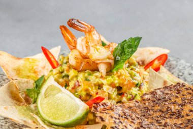 Izgara karides soslu guacamole taze limon dilimi ve seramik tabakta tortilla cipsi..