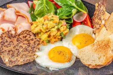 Yumurta, avokado salatası, hindi dilimleri, ıspanak, turp, keten tohumu ve kızarmış ekmek ile doyurucu bir kahvaltı tabağı.