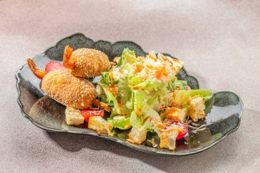 Taze Sezar salatası, kıtır ekmek, kiraz domatesleri ve rendelenmiş peynirle servis edilen kızarmış karides..