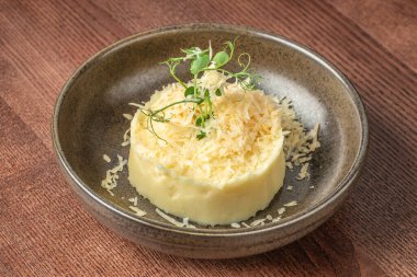 Kremalı patates püresi rendelenmiş peynir ve kırsal seramik kasede mikro yeşillikler..