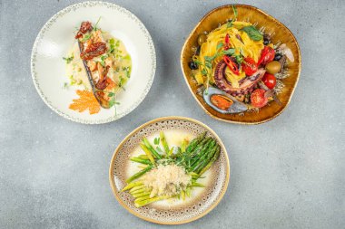 İçinde deniz ürünleri tagliatelle, krema soslu ızgara somon ve zanaatkar tabağında kuşkonmaz risotto bulunan üçlü gurme yemekleri..