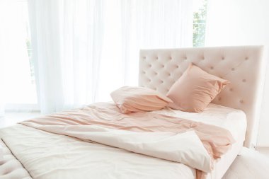 Rahat, modern yatak odası yapılmamış yatak odası ve yumuşak pembe yatak örtüsü.