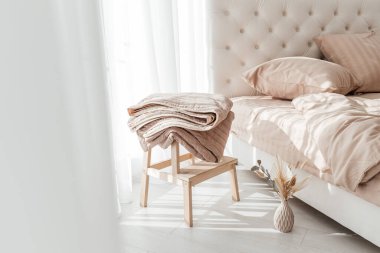 Güneşli bir sabahta, ahşap tabureye katlanmış, rahat, bej bir battaniye..