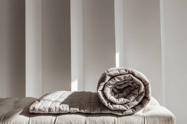 Döşeme üzerine sarılmış bej yorgan doğal güneş ışığı altında, rahat ev içi..