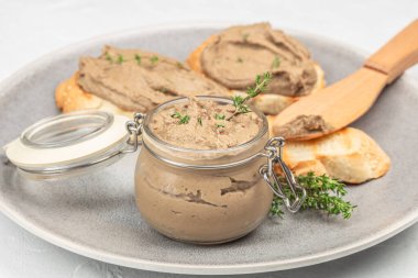 Taze kekik ile süslenmiş cam krema kavanozu, Gri bir tabakta kızarmış ekmek dilimleri ile servis edilir ahşap yayıcı, yakın görüş.