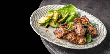 Izgara et, salatalık salatası, marul ve çizgili tabakta otlarla servis edilir..