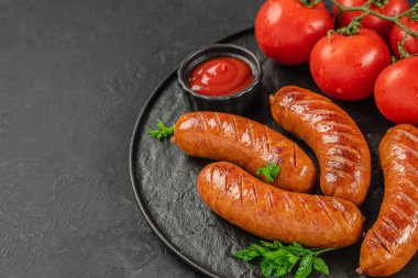 Taze domatesli ızgara sosis, maydanoz ve siyah servis tabağında ketçap. Üst Manzara. Boşluğu kopyala.