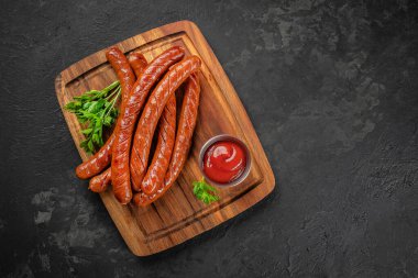 Ahşap tahtada uzun ızgara sosis, ketçap ve maydanoz. Üst Manzara. Boşluğu kopyala.